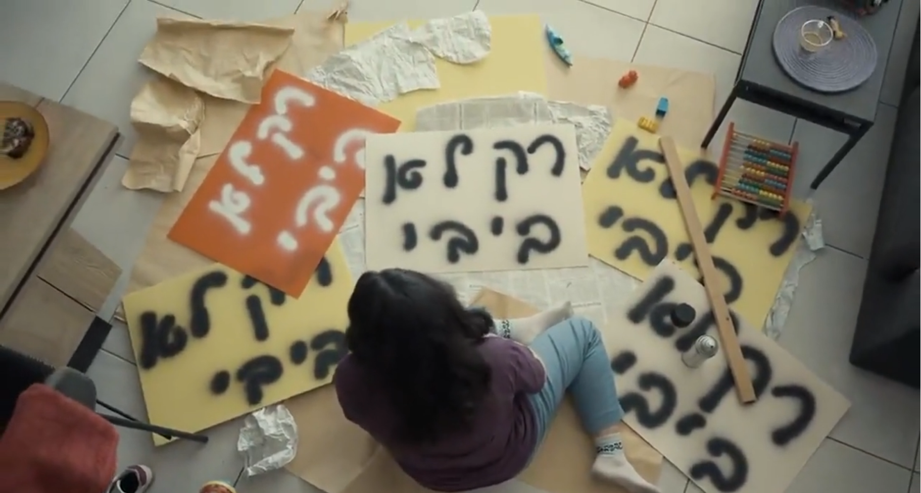  a mother is seen working on a series of posters which say "Rak Lo Bibi" (Anyone but Netanyahu)